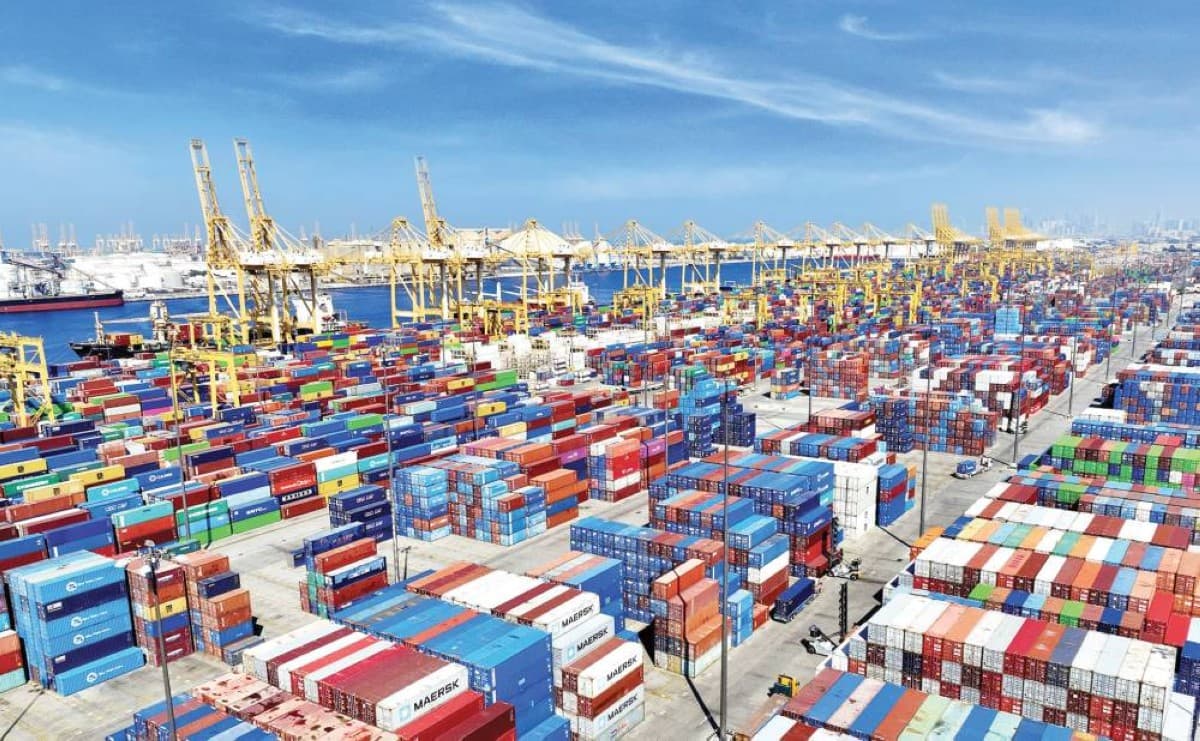Aerial view of a DP World container terminal with rows of shipping containers and port cranes.