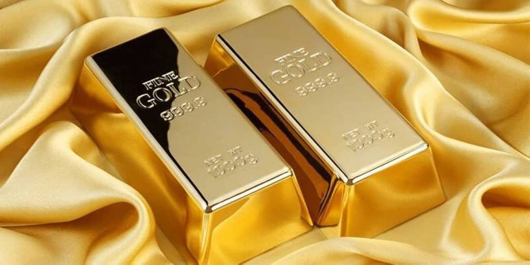 Gold bullion bars and coins representing falling precious metal prices amid rising interest rate expectations.