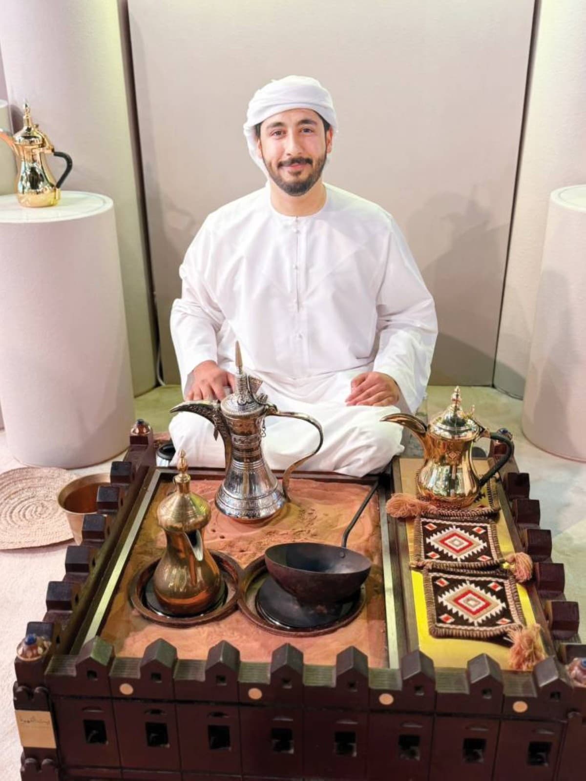 Saif Al Maamari demonstrates the traditional Emirati coffee preparation ritual, using heritage dallah pots and a mortar and pestle during a cultural event in Abu Dhabi.
