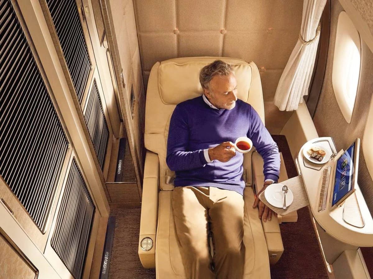 An Emirates airline first-class suite cabin on board an A380 aircraft, featuring a private enclosed suite with luxury seating and mood lighting.