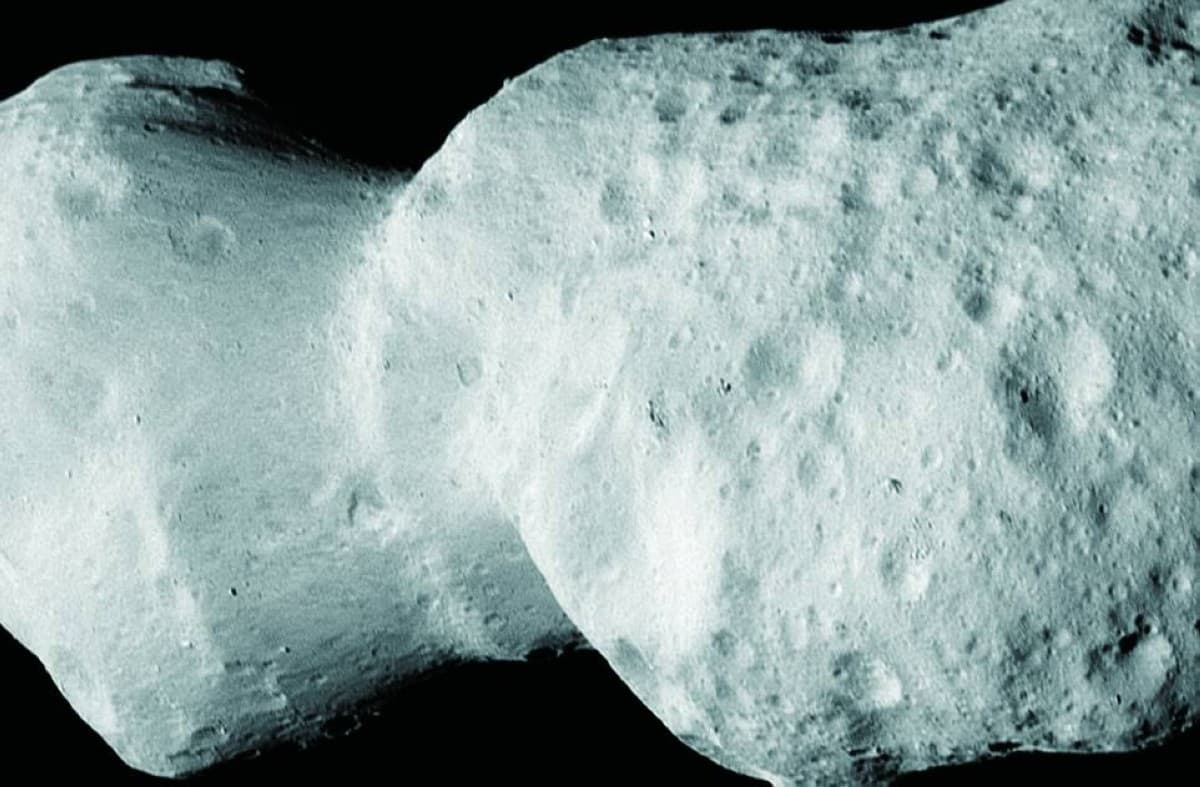 An illustration of the asteroid Donald Johanson as observed by NASA's Lucy spacecraft, resembling a peanut shape tumbling through space.