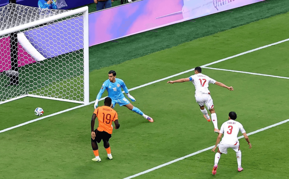 An Arab defender deflecting the ball into his own net during a World Cup match, as teammates and opponents look on in dismay.