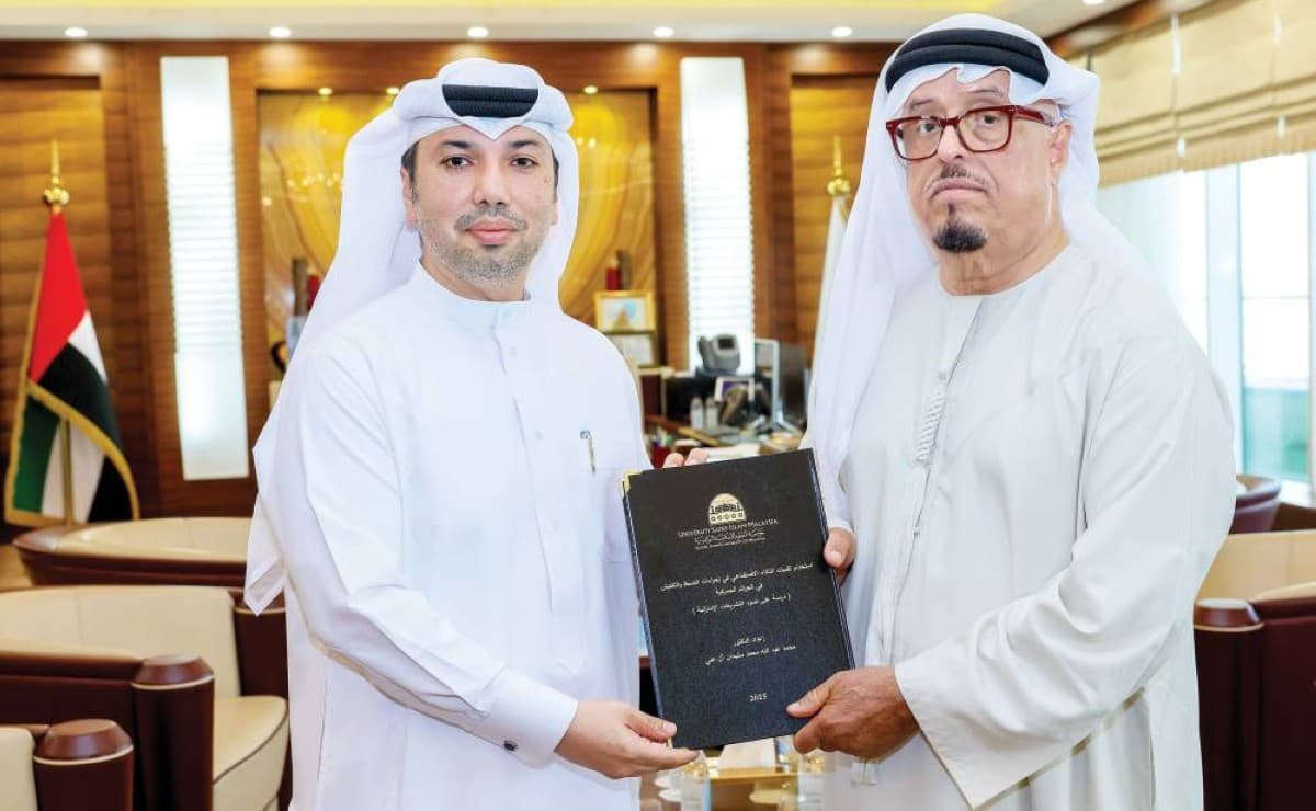 Lieutenant General Dahi Khalfan Tamim receives a copy of a doctoral thesis on artificial intelligence in customs inspection from Dr Mohammed Abdullah Al Ali at his office in Dubai.