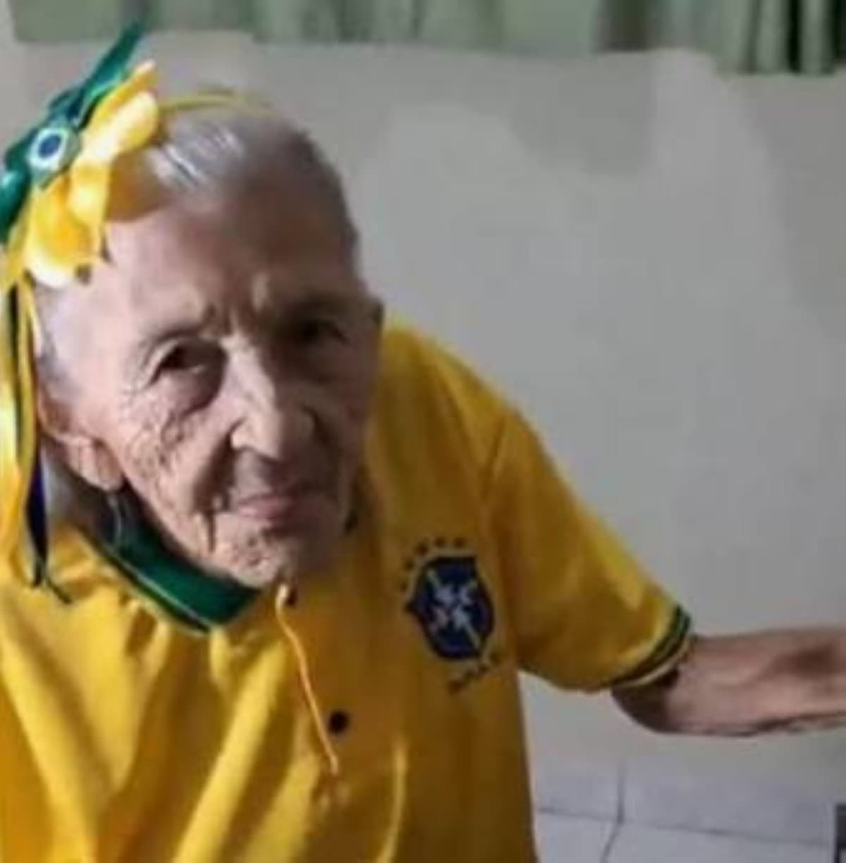 Dona Maria, a 104-year-old Brazilian fan, dressed in the yellow national team shirt and adorned with green and yellow accessories to support the Seleção at the 2026 World Cup.