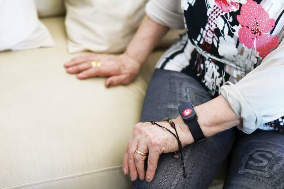 A smart electronic bracelet worn on a wrist, designed to monitor elderly residents' health and enable emergency alerts in Rome.