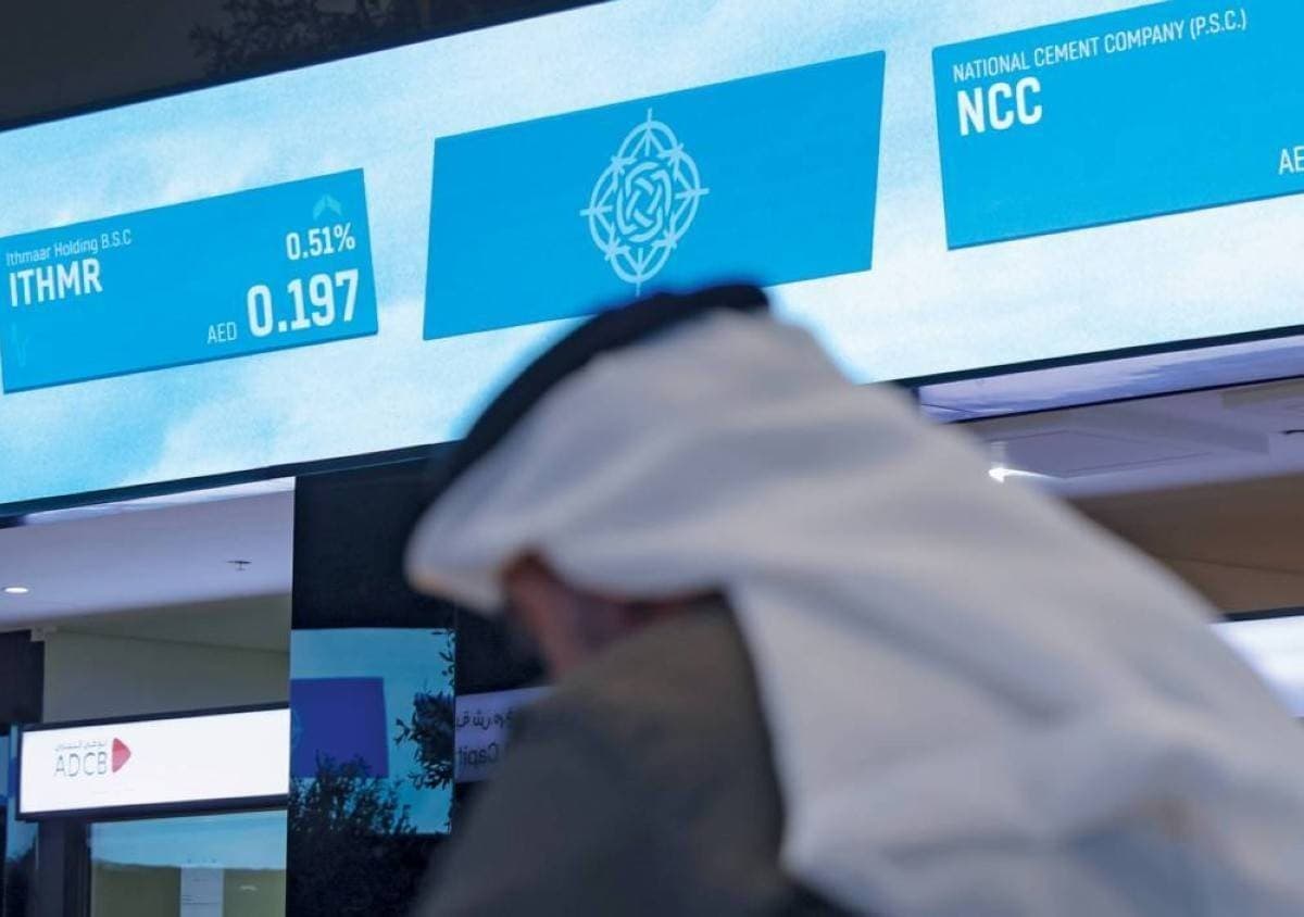 Traders monitor stock market data on screens displaying UAE equity indices and trading activity.