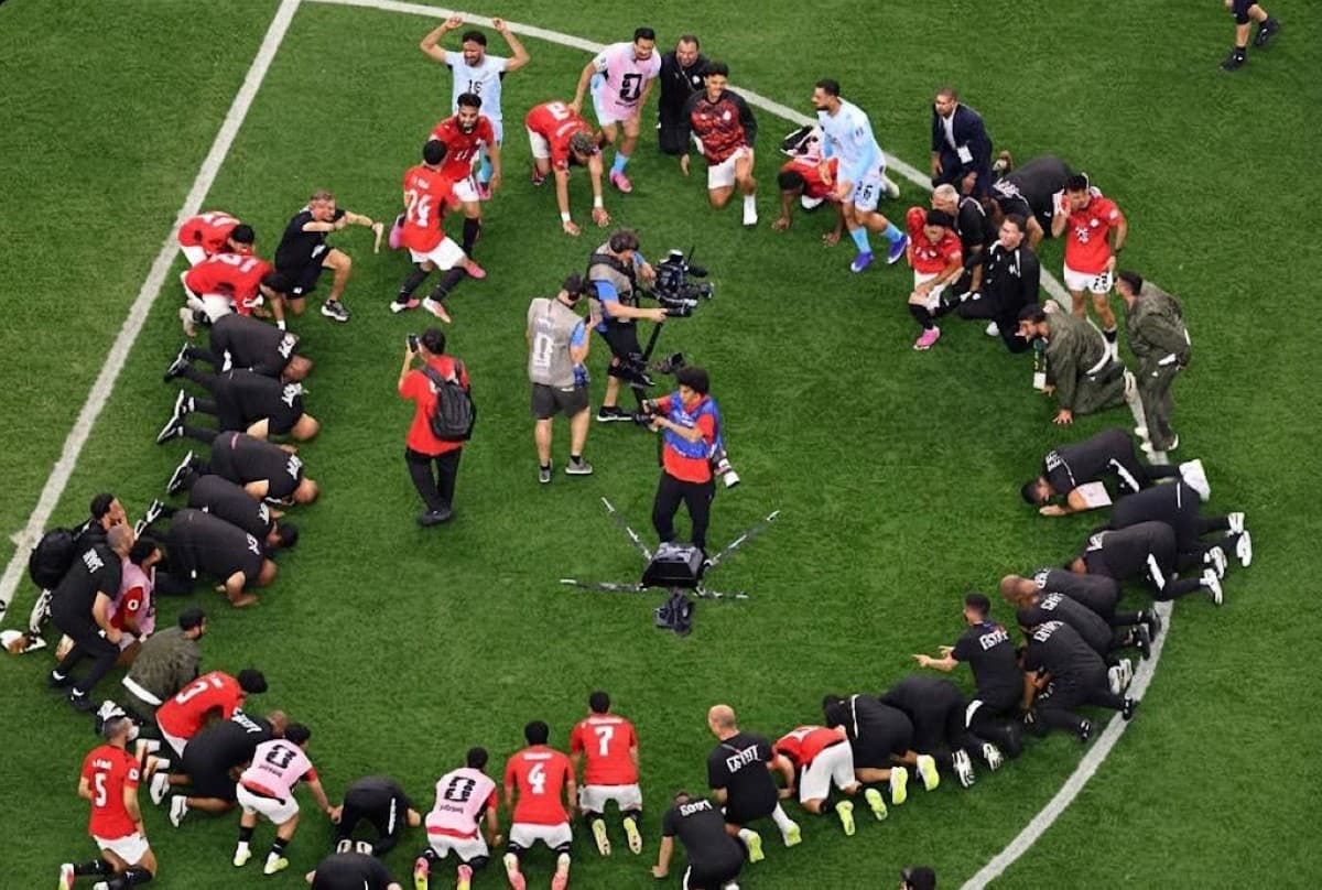 Egypt national team players and coaching staff perform a collective prostration of thanks on the pitch after qualifying for the round of 16 at the 2026 FIFA World Cup.