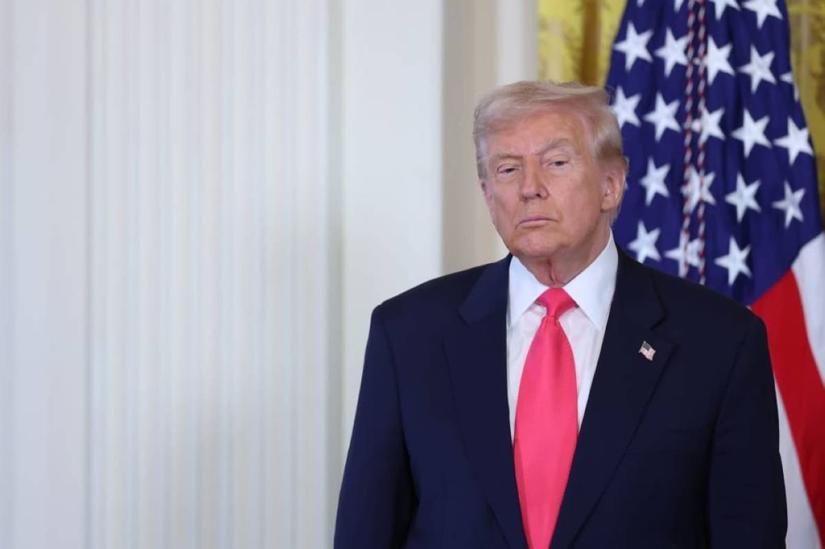 US President Donald Trump speaking during an interview, with the White House visible in the background.