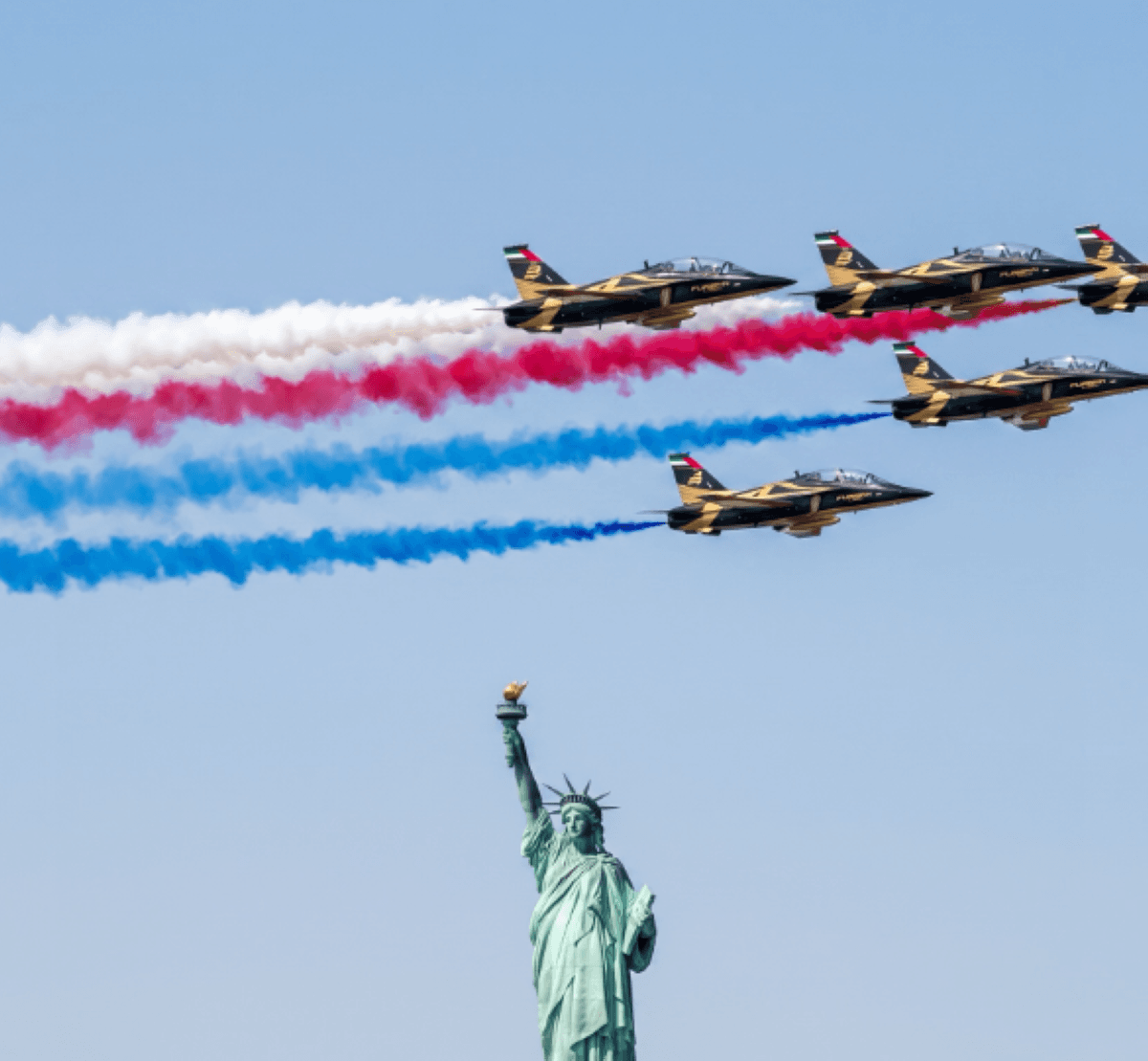 The UAE Falcons aerobatic team flying in formation over New York, with smoke trails in the colours of the UAE flag visible against the city skyline during the Sail Forth 250 celebrations.