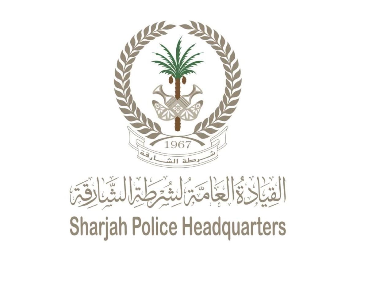 Sharjah Police officers displaying seized items including bank cards, passports, electronic devices, and documents recovered during the electronic fraud network operation.