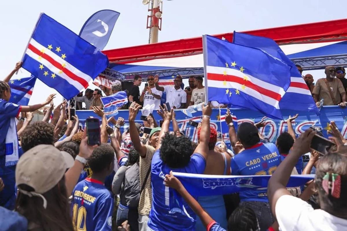 Cape Verde national football team players ride through the streets of Praia during a celebratory motorcade, greeted by thousands of cheering fans lining the route.