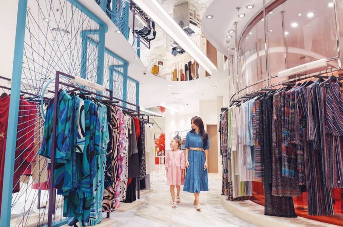 Shoppers browse retail stores at a Dubai shopping centre during the Dubai Summer Surprises season, with promotional banners and discount signs on display.