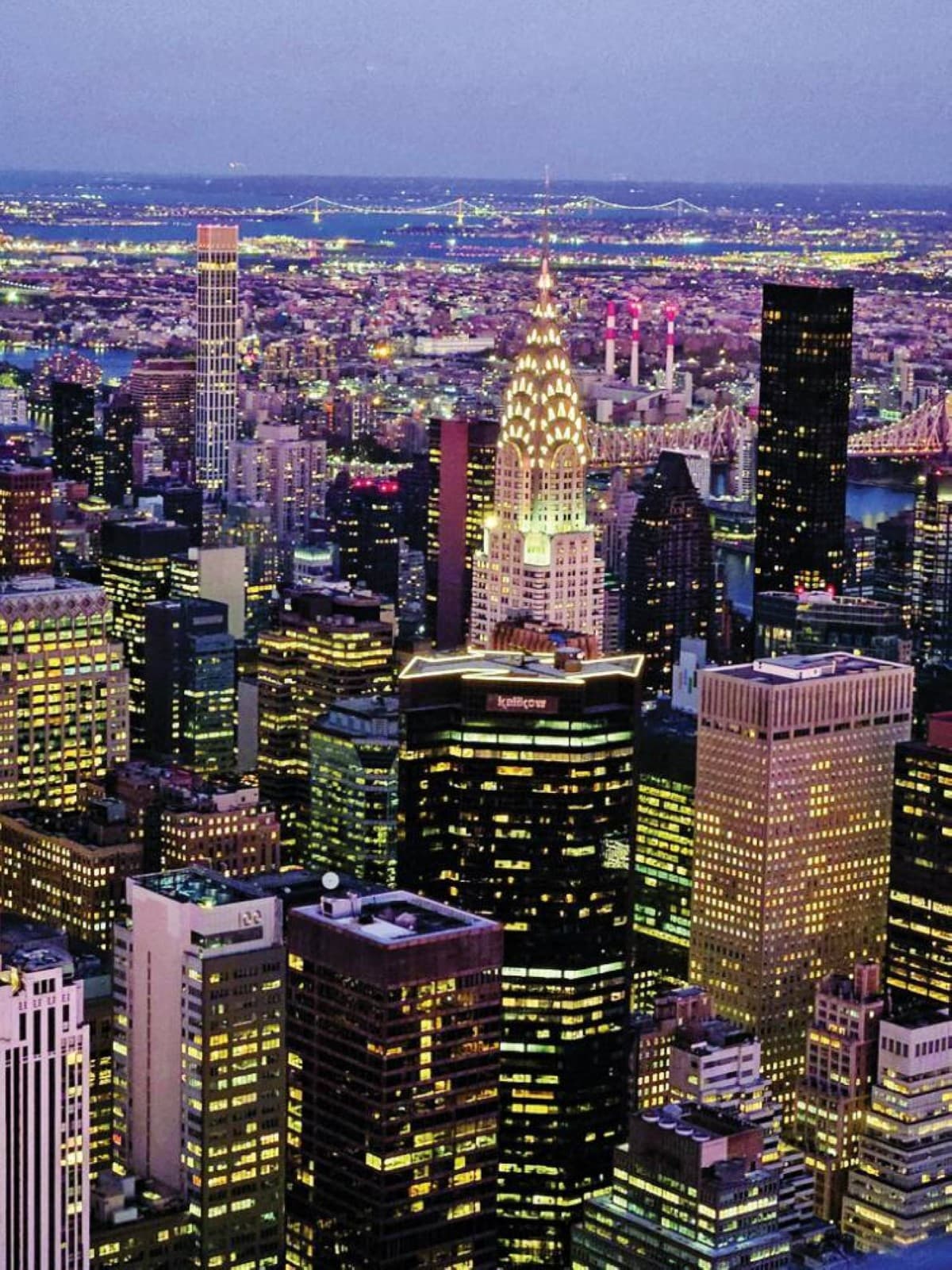 A wide-angle view of Times Square in New York City, with giant illuminated screens covering the facades of surrounding skyscrapers and crowds of tourists filling the square below.