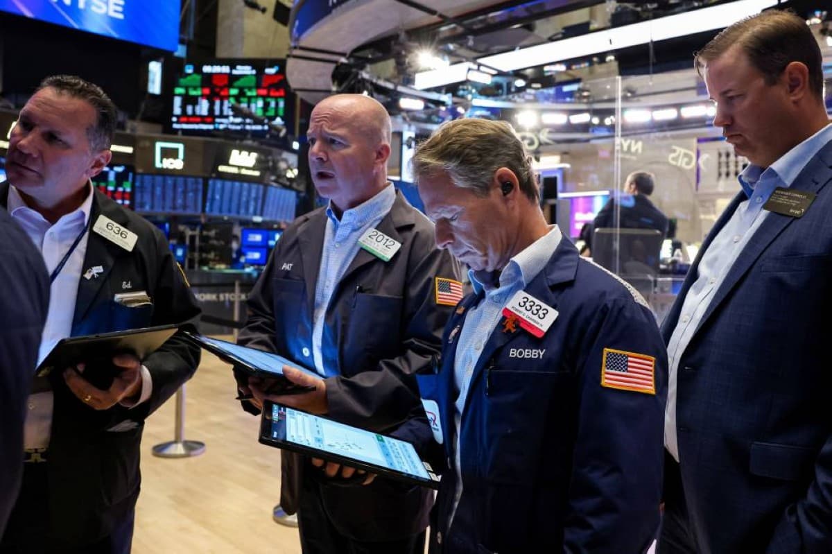 A display board showing declining figures for major US stock market indices including the Dow Jones, Nasdaq, and S&amp;P 500.