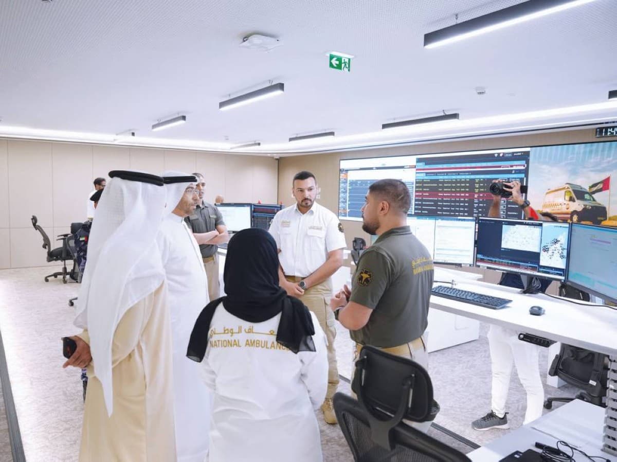 Health minister Ahmed bin Ali Al Sayegh tours the new National Ambulance headquarters in Abu Dhabi alongside officials and ambulance fleet vehicles.