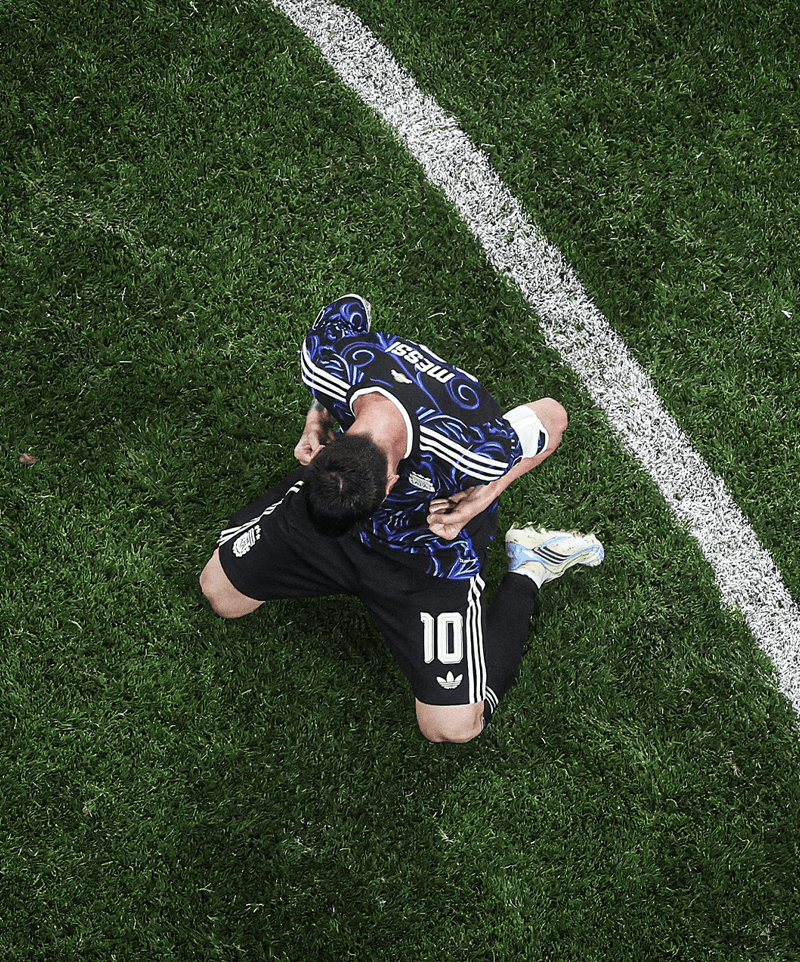 Lionel Messi sits on the pitch and celebrates with teammates after Argentina defeat England 2-1 in the 2026 World Cup semi-final.