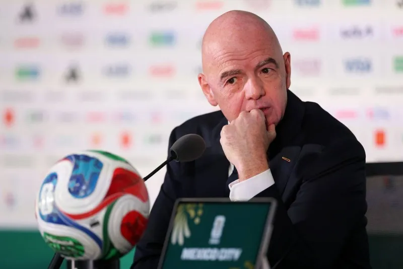 FIFA president Gianni Infantino speaking at a press conference, with Italy's national football team colours visible in the background.