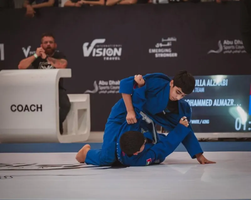 Young jiu-jitsu athletes competing on the mat at Mubadala Arena in Abu Dhabi during the UAE National Jiu-Jitsu Championship.