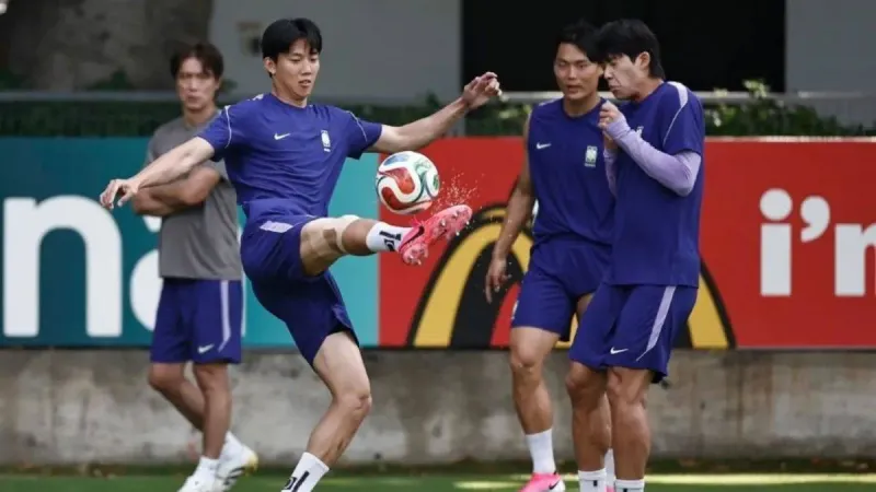South Korea head coach Hong Myung-bo takes a player's phone during a training recovery session as teammates and staff look on smiling.