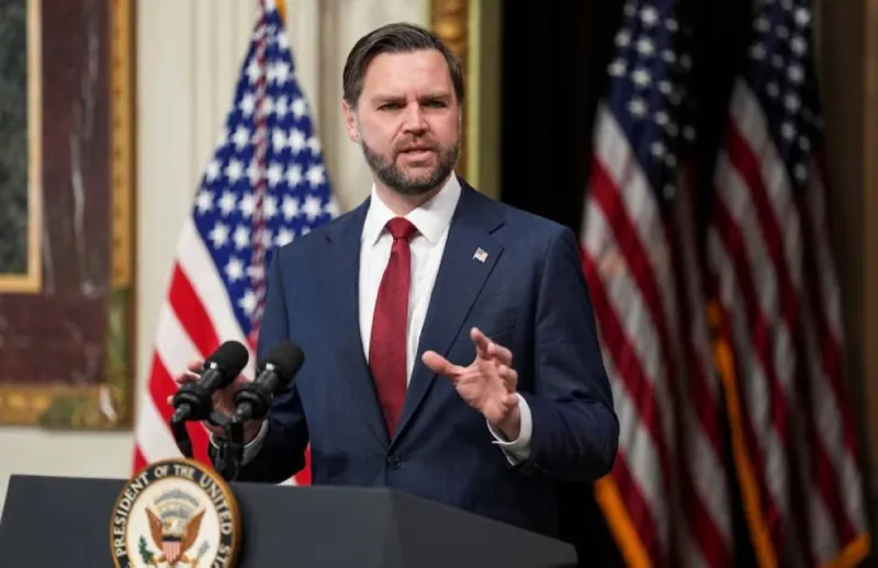 US Vice President JD Vance speaking at a press event, with a backdrop suggesting an official government setting.