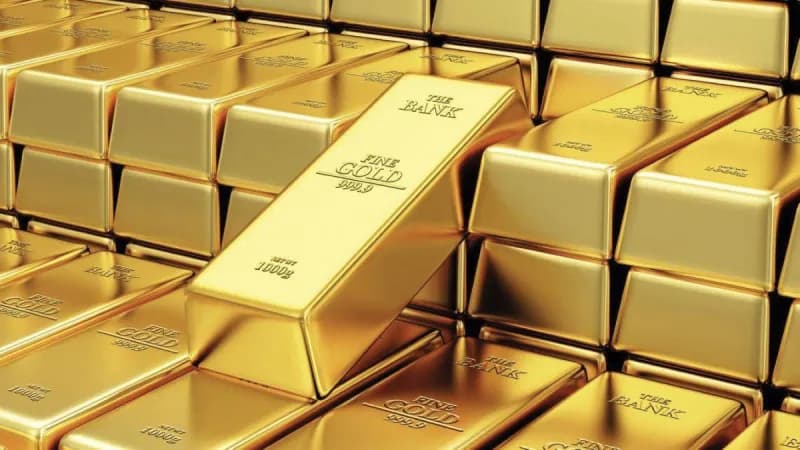 Gold bars and coins displayed against a dark background, reflecting rising precious metals prices.