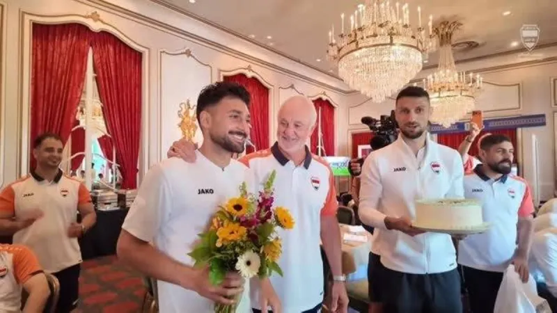 Iraq national team players gather around defender Frans Botros to celebrate the birth of his newborn child with flowers and a cake inside the team's training camp.