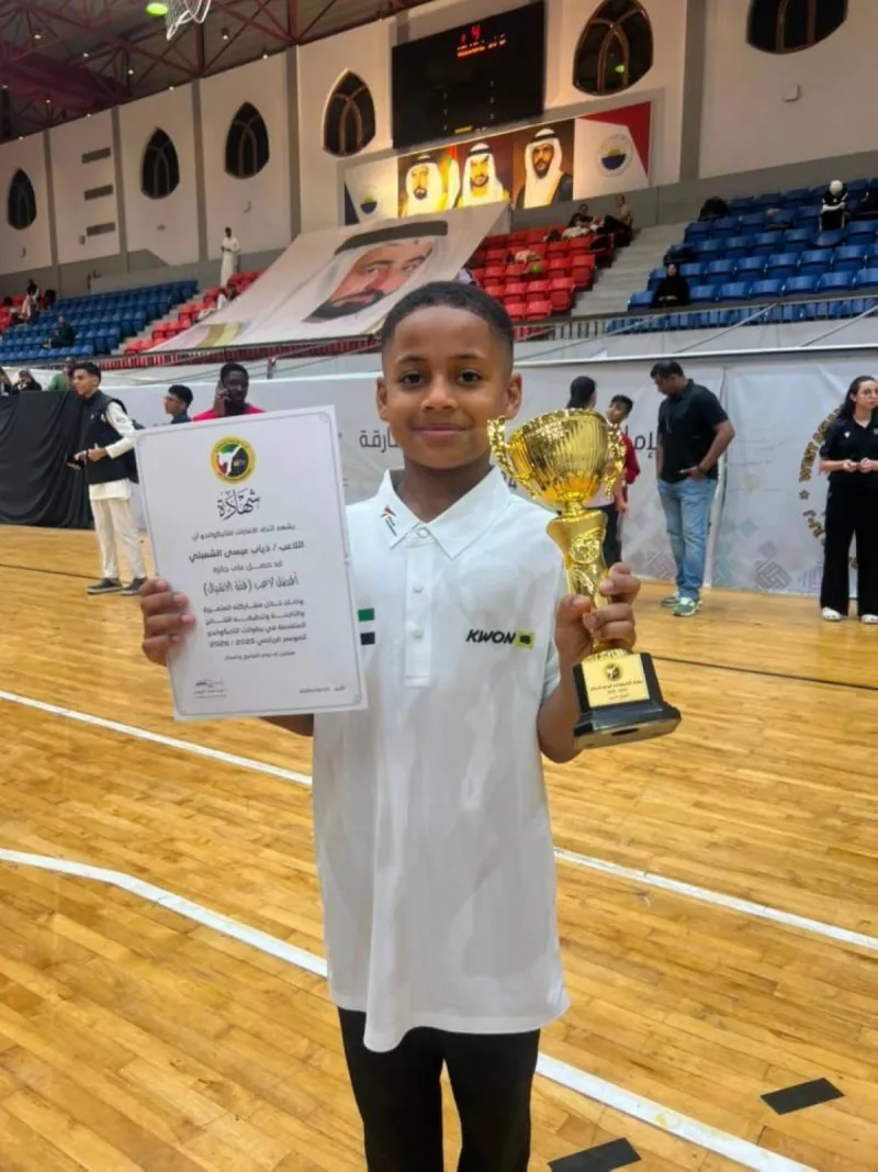 Young Emirati taekwondo player Dhiyab Al Shmeili, aged 9, poses with his Best Player award from the UAE Taekwondo Federation's Cubs category for the 2025–2026 season.