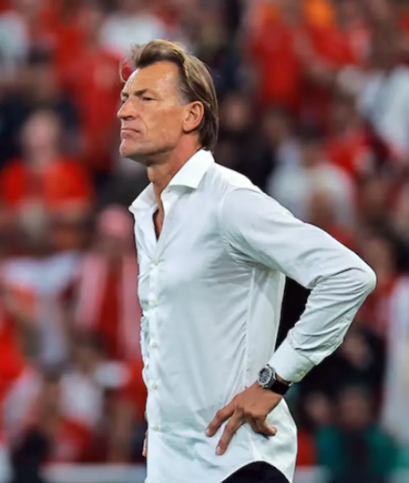 Hervé Renard stands on the touchline in his signature white shirt during a World Cup match, looking intently at the pitch.