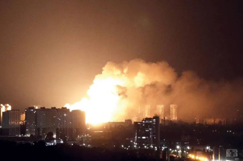 Drone and missile smoke trails visible over a city skyline during a night attack in the Russia-Ukraine war.