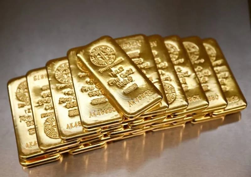 Gold bars and coins displayed against a dark background, representing the precious metals market.