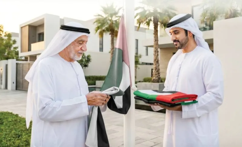 The UAE national flag flying above a residential building in Abu Dhabi, illustrating the municipality's call to replace faded or damaged flags.