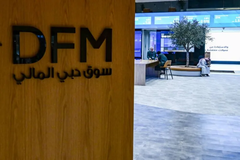 Traders monitoring stock screens showing gains in the Dubai Financial Market and Abu Dhabi Securities Exchange indices.