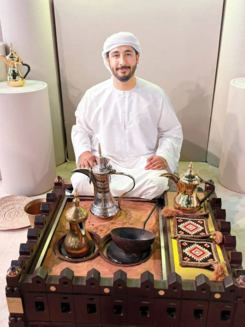 Saif Al Maamari demonstrates the traditional Emirati coffee preparation ritual, using heritage dallah pots and a mortar and pestle during a cultural event in Abu Dhabi.