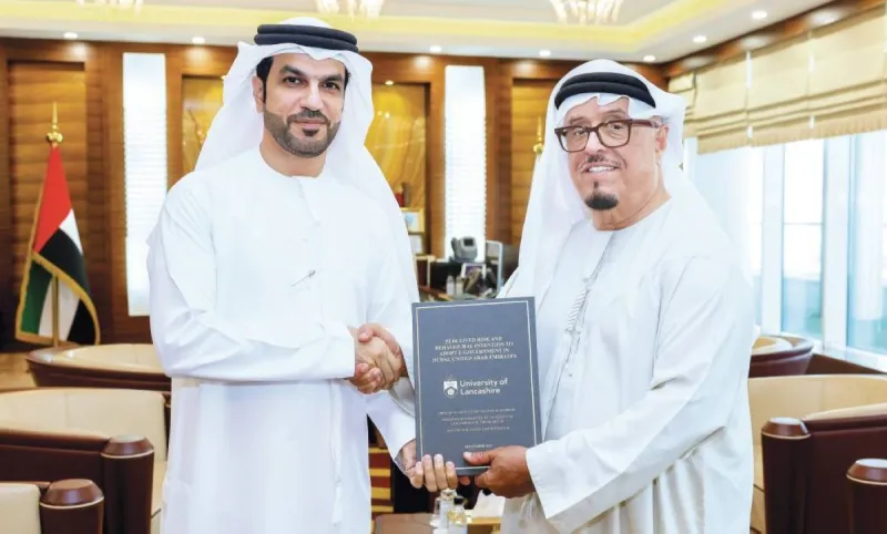 Lieutenant General Dhahi Khalfan Tamim receiving a copy of a doctoral thesis on e-government services from Dr Ibrahim Salman Al Hamadi at his office in Dubai.