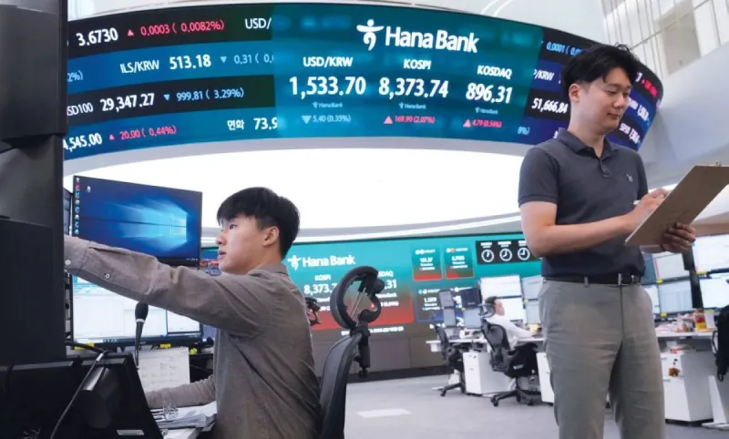 Traders monitor global stock market indices on screens in a financial trading room amid a cautious session driven by technology earnings anticipation and geopolitical developments.