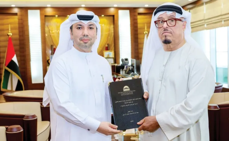 Lieutenant General Dahi Khalfan Tamim receives a copy of a doctoral thesis on artificial intelligence in customs inspection from Dr Mohammed Abdullah Al Ali at his office in Dubai.