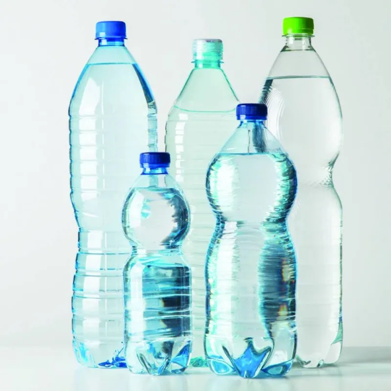 A plastic bottle alongside graphite material used in electric vehicle battery manufacturing.