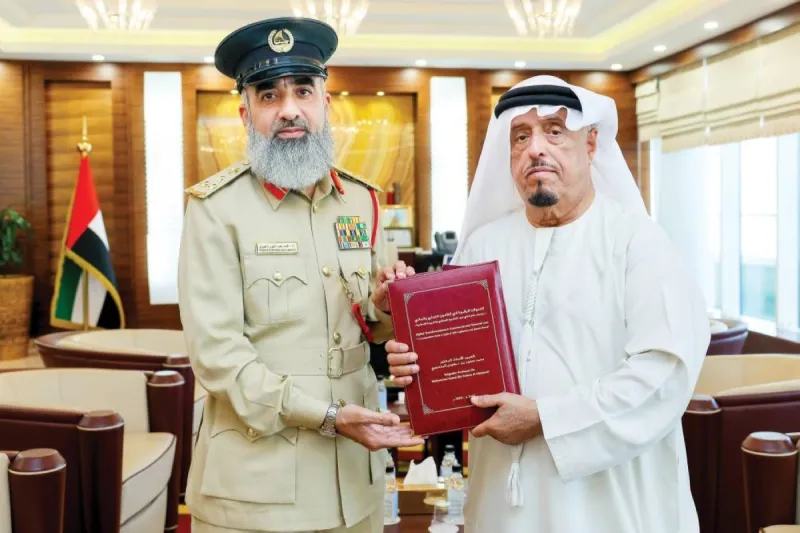 Lieutenant General Dahi Khalfan Tamim receiving a book on digital transformations in commercial and financial law from Brigadier Professor Dr. Mohammed Saeed bin Da'fous Al Mansouri at Dubai Police Academy.