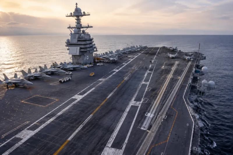 The flight deck of an aircraft carrier at sea, showing its steel non-slip surface with fighter jets positioned for operations.