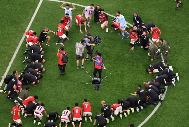 Egypt national team players and coaching staff perform a collective prostration of thanks on the pitch after qualifying for the round of 16 at the 2026 FIFA World Cup.