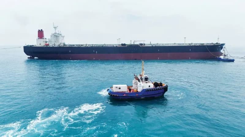 A convoy of oil tankers navigating the Strait of Hormuz along the Omani coastline.