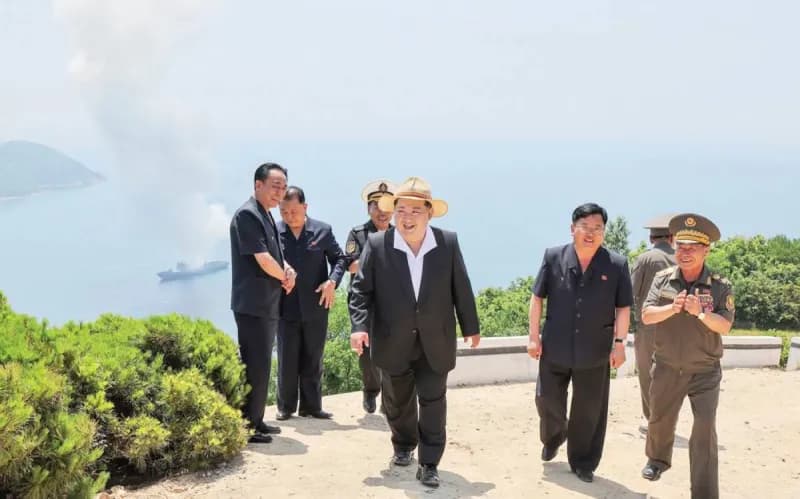 North Korean leader Kim Jong Un observes weapons tests aboard the destroyer Kang Kun from a coastal observation post, surrounded by officials.