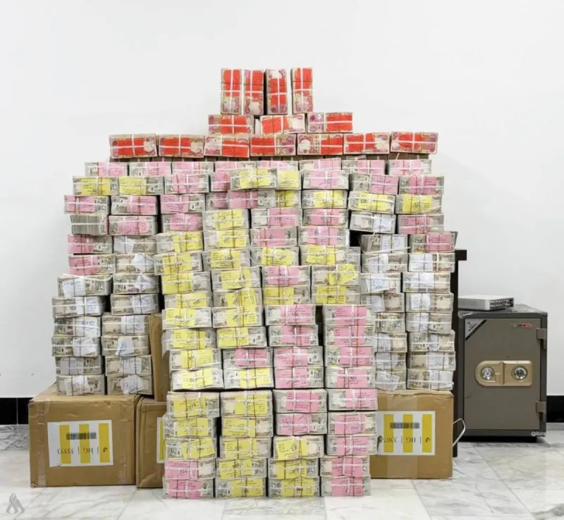 Iraqi security forces and judicial officials oversee the counting of cash seized during a corruption investigation, including funds reportedly hidden inside plastic water bottles at a home in Tikrit.