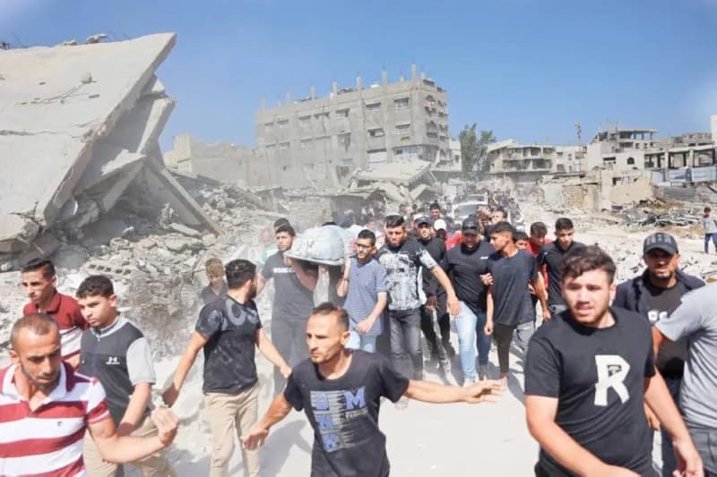 Palestinian civilians and officials amid the ruins of buildings in Gaza, reflecting the ongoing humanitarian and political transition in the territory.