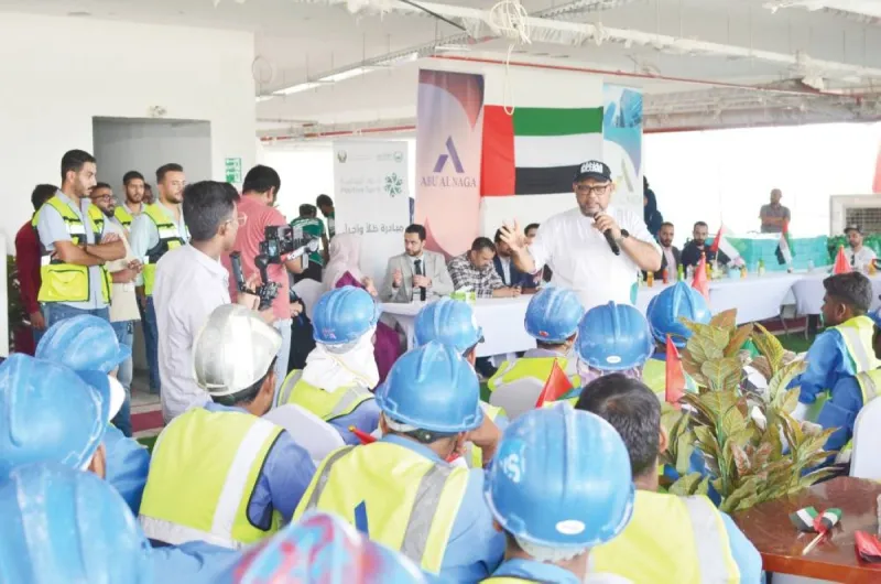 Workers at the Burj Versailles construction site in Wadi Al Safa receiving cold water, meals, and umbrellas as part of Dubai Police's 'Shade and Wage' heat stress prevention initiative.