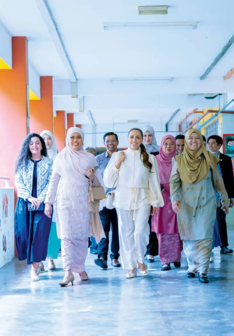 Sheikha Badour bint Sultan Al Qasimi visits a school in Malaysia as part of Kalimat Foundation's mobile library initiative, surrounded by students and officials.