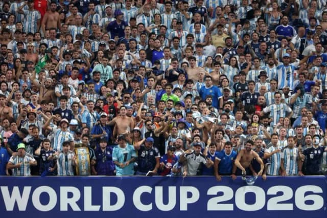 Fans in stadium stands cheering and chanting passionately during a 2026 World Cup match.